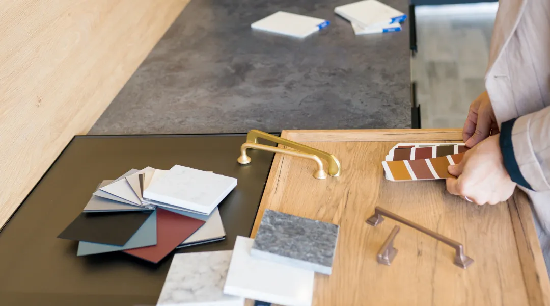 A kitchen designer holds a paint sample, considering color options for a project.