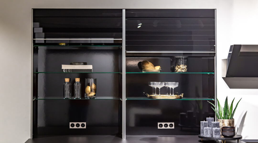 Black glass cabinet with glass shelves and a vase, ideal for kitchen storage.