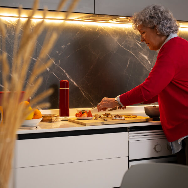 Une femme en pull rouge cuisine, illustrant le thème : Pourquoi rénover sa cuisine en 2025 ?